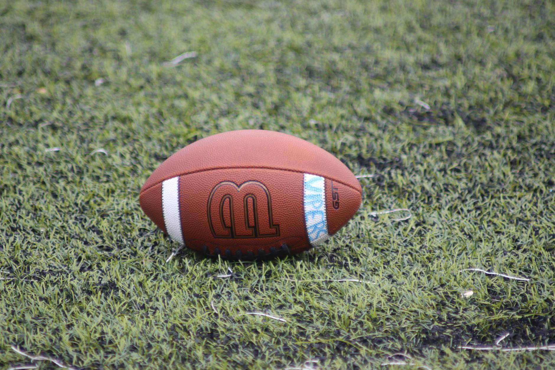 Close-up of a football resting on a grass field, perfect for sports themes.