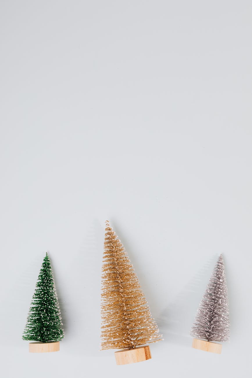 Elegant minimalist Christmas trees in green, gold, and silver shades on white background.