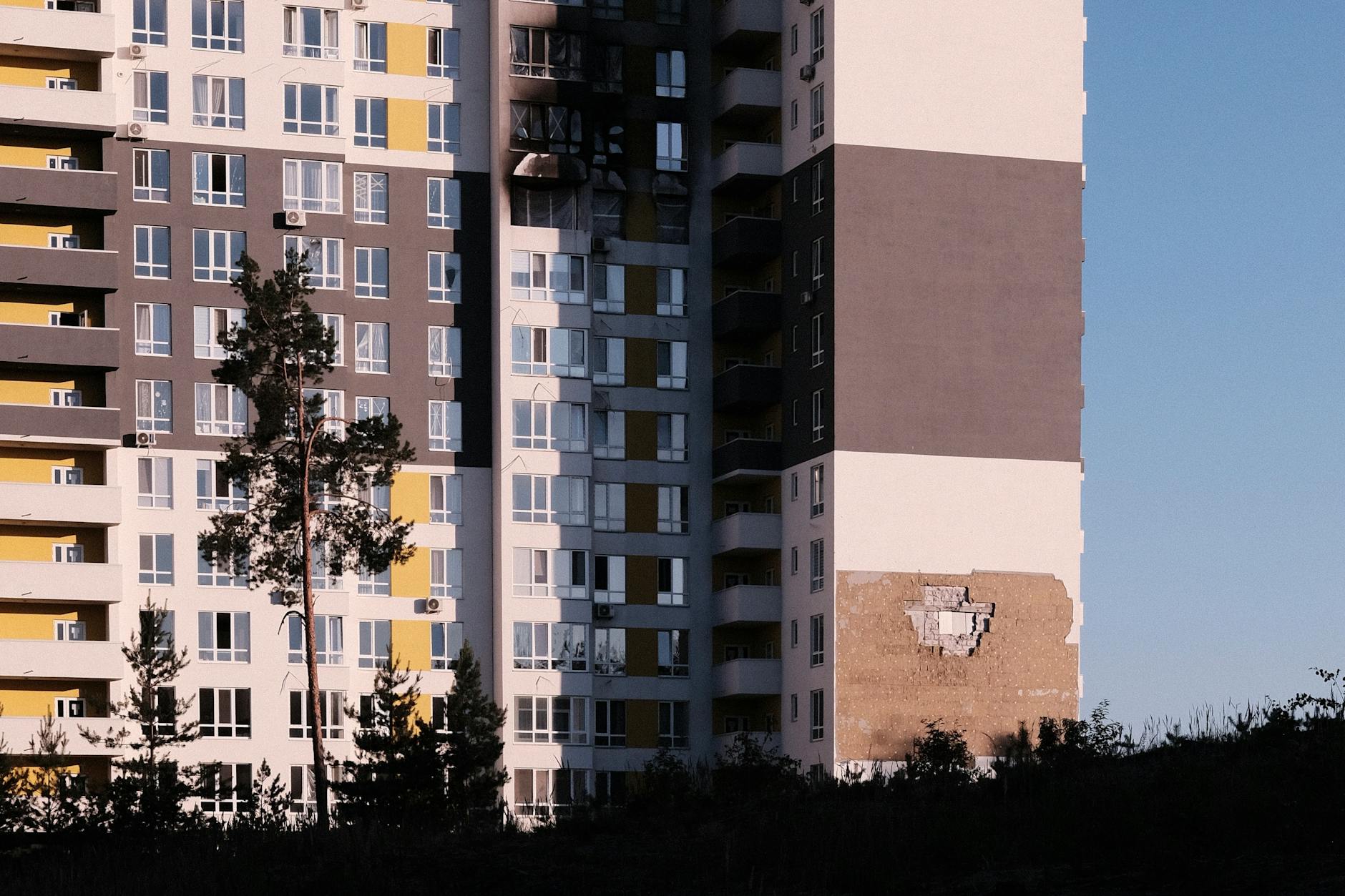 Exterior view of a modern apartment building in Ukraine showing visible damage to the structure.