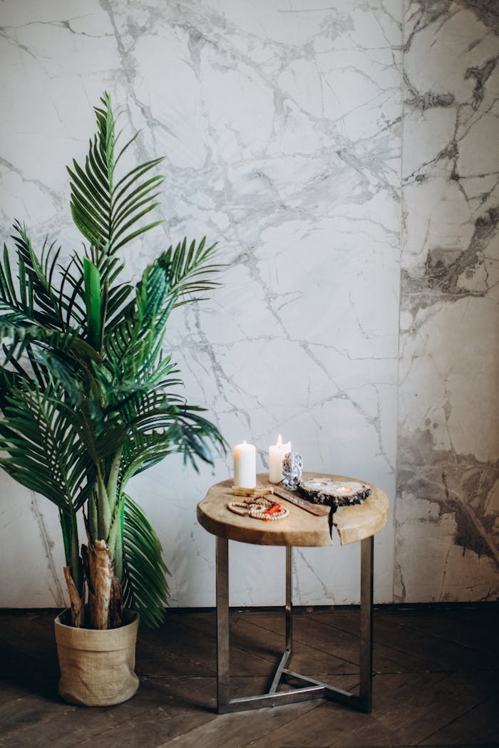 services-04 A serene indoor decor scene featuring candles, a potted plant, and prayer beads on a wooden table.